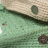 Close-up detail of Atelier Bagatelle's Riviera Lili crocheted bags in sage green and natural beige with logo