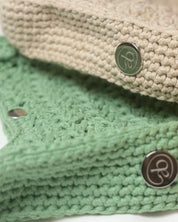 Close-up detail of Atelier Bagatelle's Riviera Lili crocheted bags in sage green and natural beige with logo