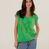 Front view of a model styling the green straight-cut Molly t-shirt with classic blue denim jeans.