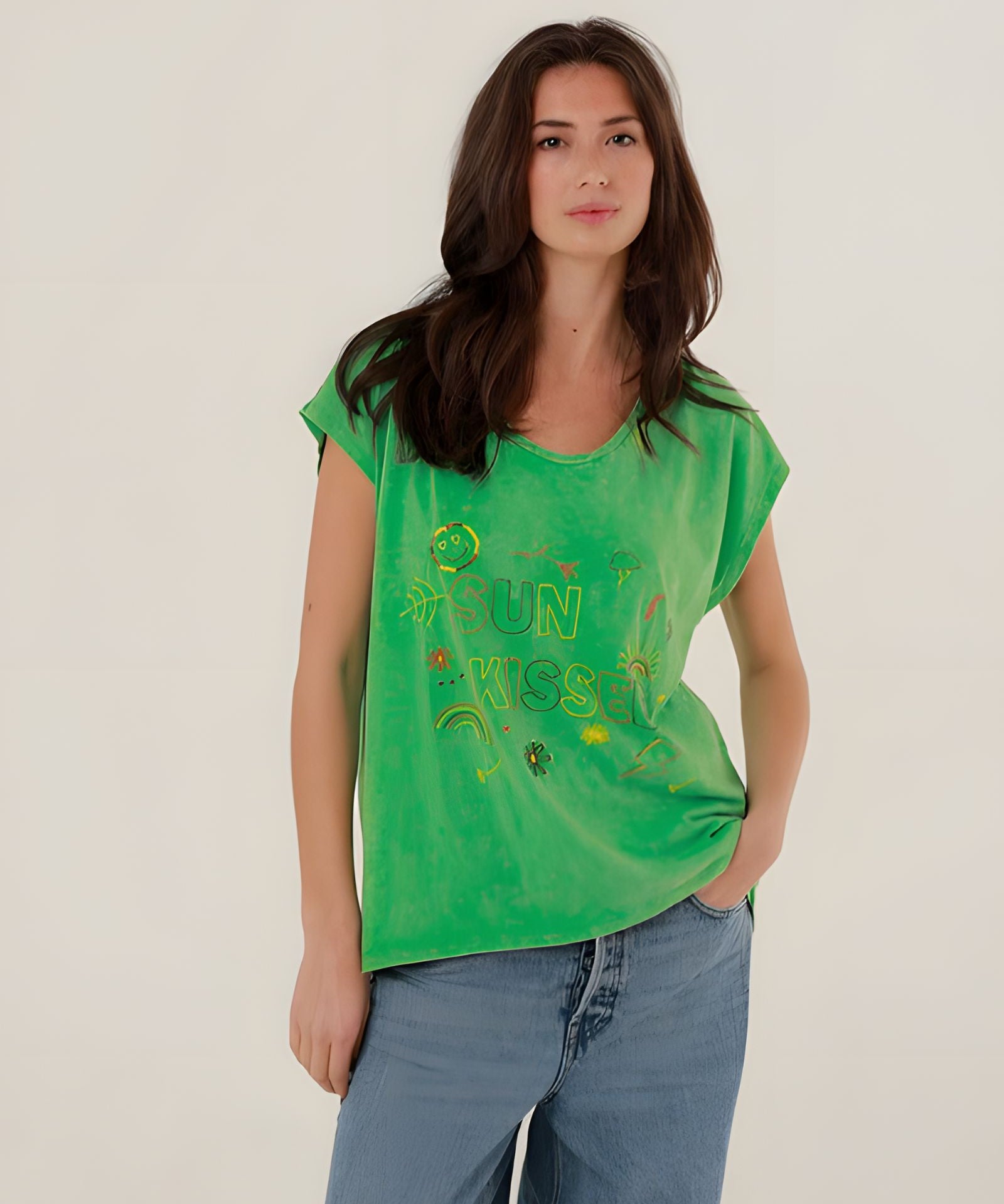 Front view of a model styling the green straight-cut Molly t-shirt with classic blue denim jeans.