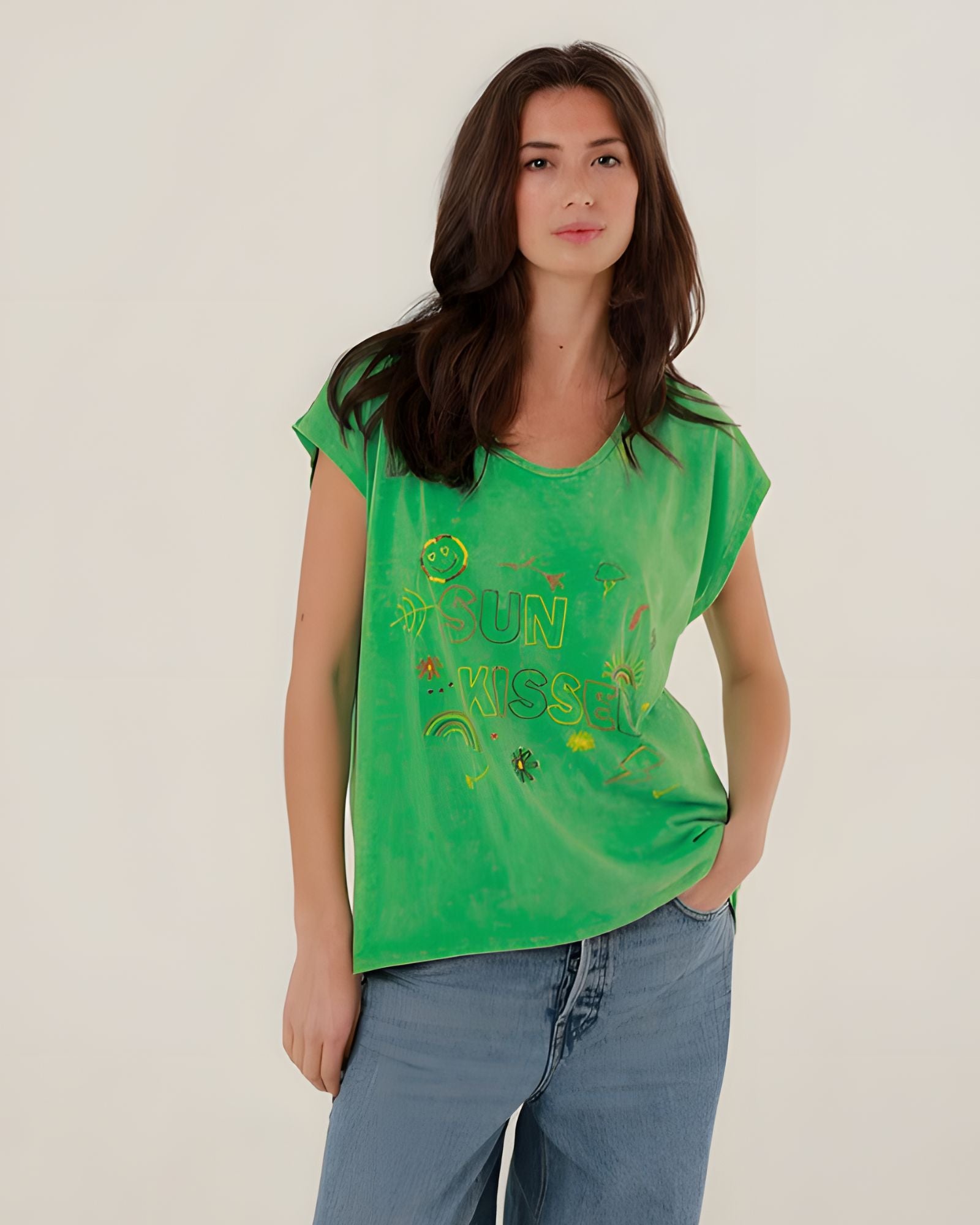 Front view of a model styling the green straight-cut Molly t-shirt with classic blue denim jeans.