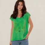 Close-up front view of a model wearing the vibrant green cotton Molly T-shirt with multicolored SUN KISSED chest embroidery.