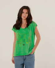 Close-up front view of a model wearing the vibrant green cotton Molly T-shirt with multicolored SUN KISSED chest embroidery.