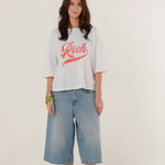 Full-length front view of a model styling the white cotton Tamara boyfriend t-shirt with wide-leg denim shorts.