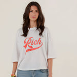 Close-up front view of a model wearing the white oversized Tamara T-shirt featuring a sparkling red rhinestone Rich script on the chest.