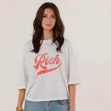Close-up front view of a model wearing the white oversized Tamara T-shirt featuring a sparkling red rhinestone Rich script on the chest.