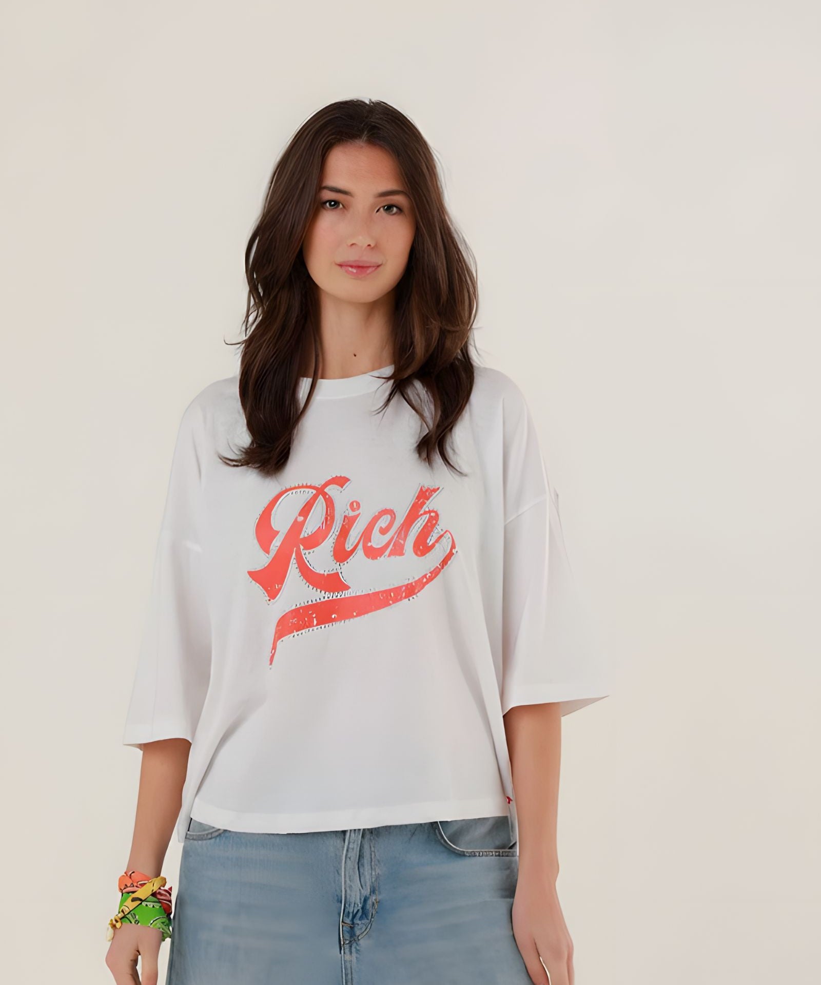 Close-up front view of a model wearing the white oversized Tamara T-shirt featuring a sparkling red rhinestone Rich script on the chest.