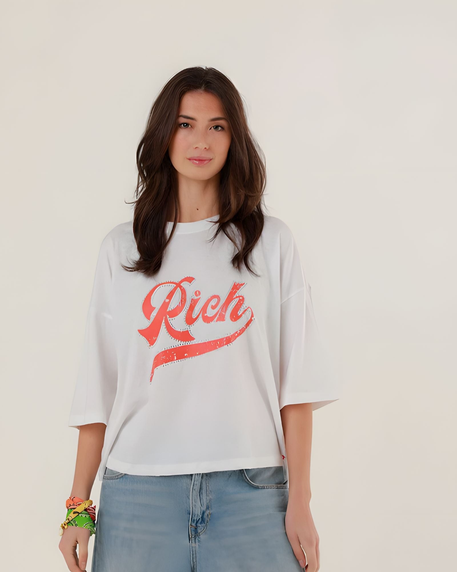 Close-up front view of a model wearing the white oversized Tamara T-shirt featuring a sparkling red rhinestone Rich script on the chest.