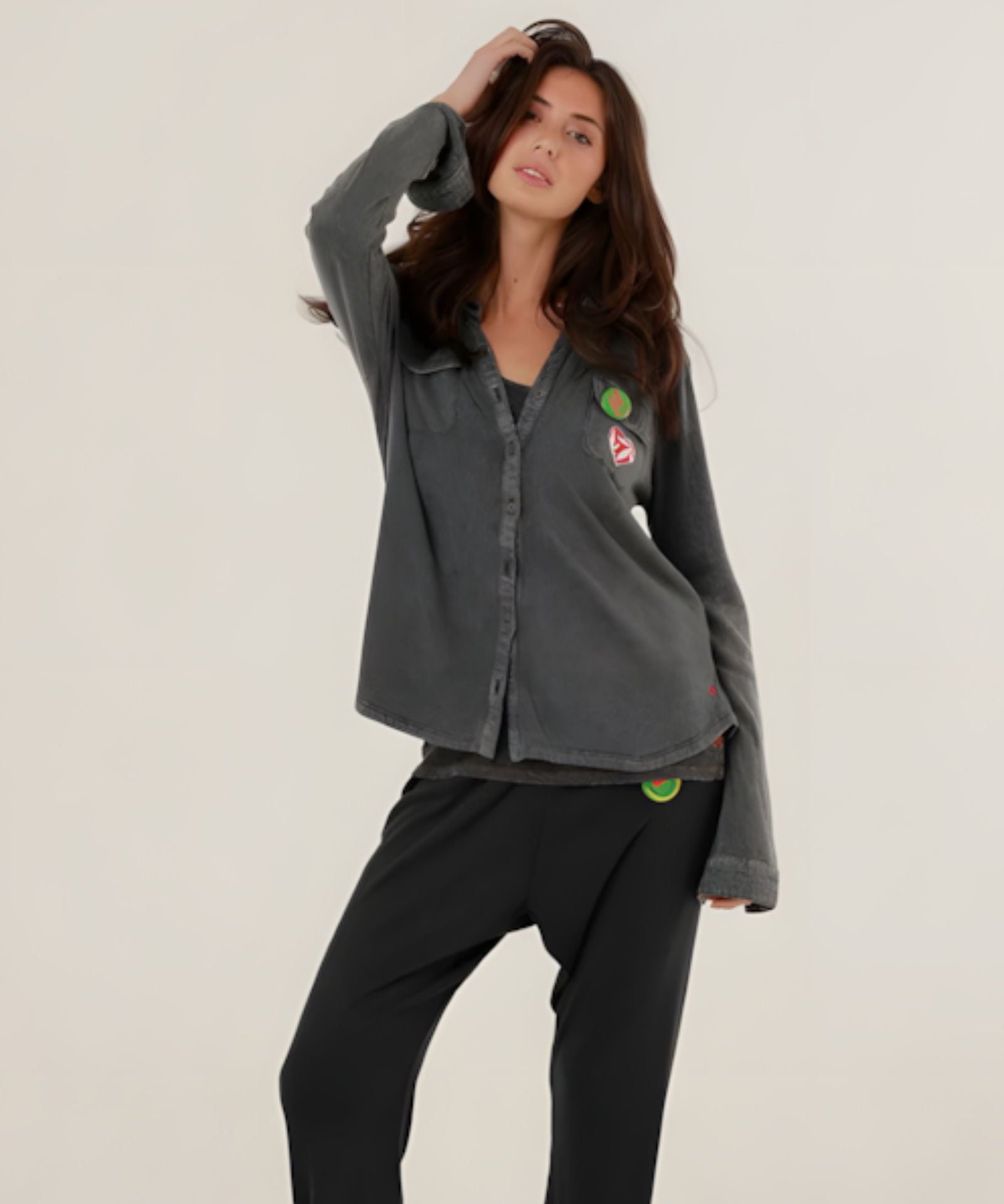 A woman wearing the charcoal carbone Tess fluid cotton-modal shirt featuring a straight cut and colorful patches, paired with matching sweatpants.