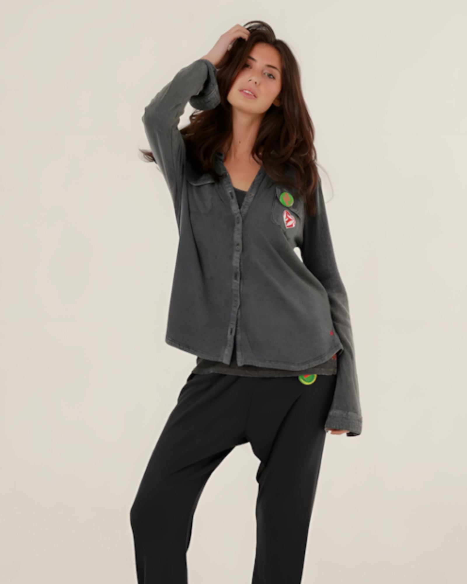 A woman wearing the charcoal carbone Tess fluid cotton-modal shirt featuring a straight cut and colorful patches, paired with matching sweatpants.