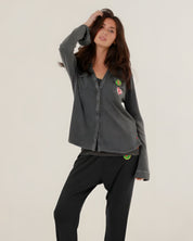 A woman wearing the charcoal carbone Tess fluid cotton-modal shirt featuring a straight cut and colorful patches, paired with matching sweatpants.