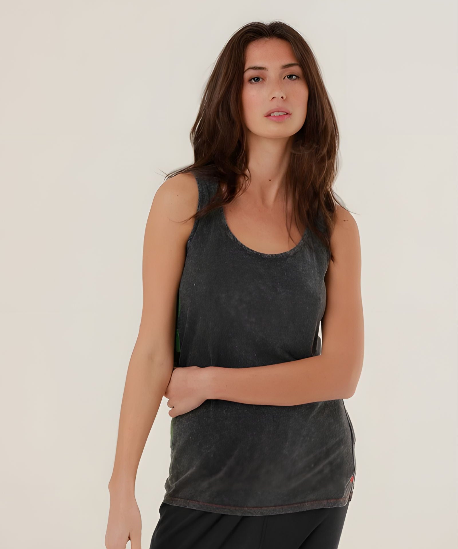 A mid-shot of a model wearing the charcoal carbone Top Mia tank top, highlighting the classic scoop neck and relaxed straight fit.