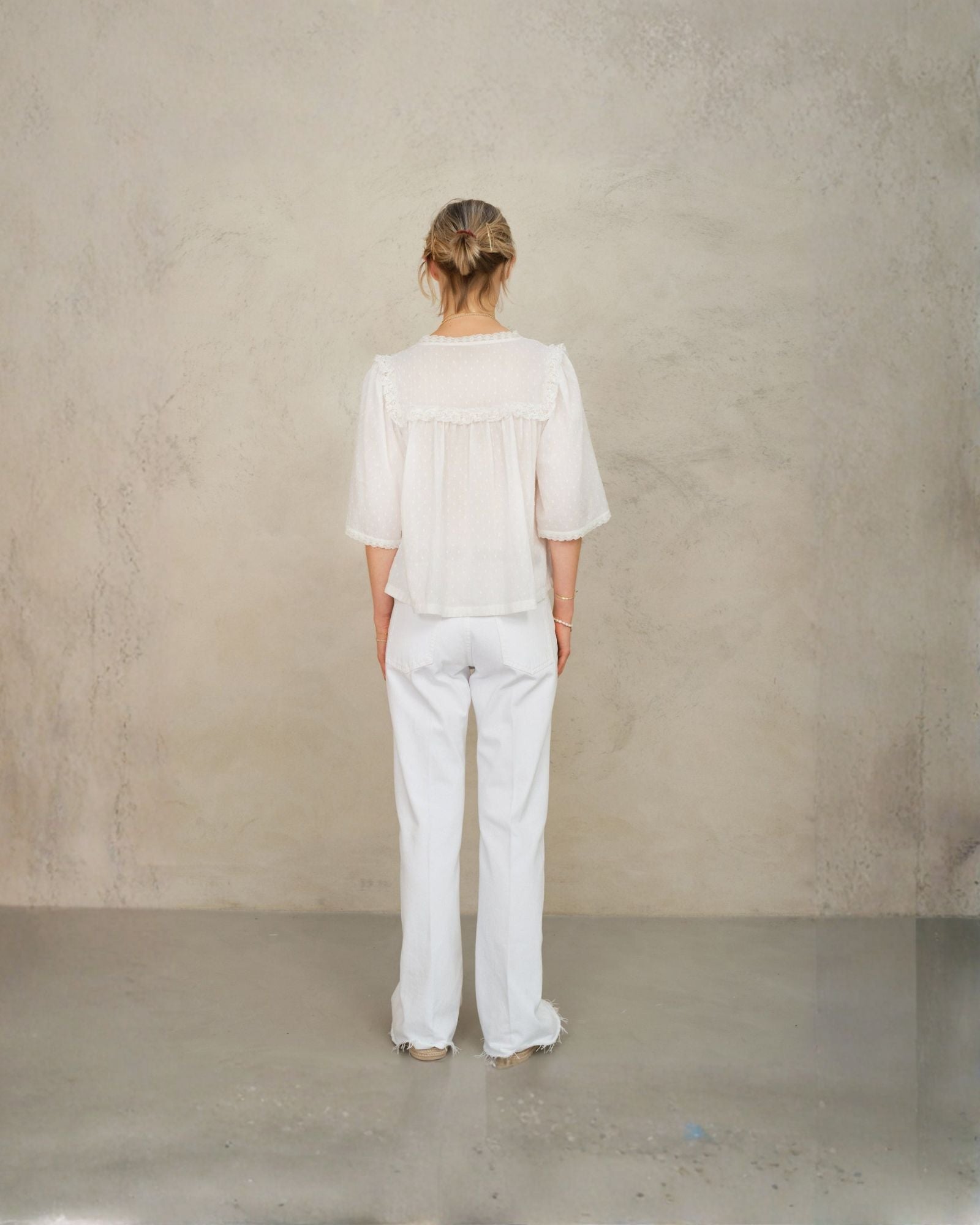 Back view of model wearing white lace cotton blouse by Mabe Apparel.