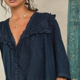 Close-up of the scalloped lace trim and floral embroidery on a Mabe Apparel navy blue blouse.