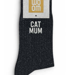 Classic black glitter message socks with a white jacquard CAT MUM inscription at the ankle, presented in their original Woom paper packaging.