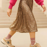 Close-up lifestyle shot of a model wearing the rose gold glitter message socks paired with a pleated gold skirt and casual sneakers.