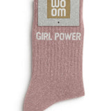 Rose gold glitter message socks with a white jacquard GIRL POWER inscription at the ankle, presented in their original Woom paper packaging.