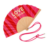Close-up view of the opened red and pink striped wooden fan, showcasing the high-quality fabric finish, contrast typography, and attached pink strap.