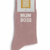 Rose gold glitter message socks with a white jacquard MUM BOSS inscription at the ankle, presented in their original Woom paper packaging.