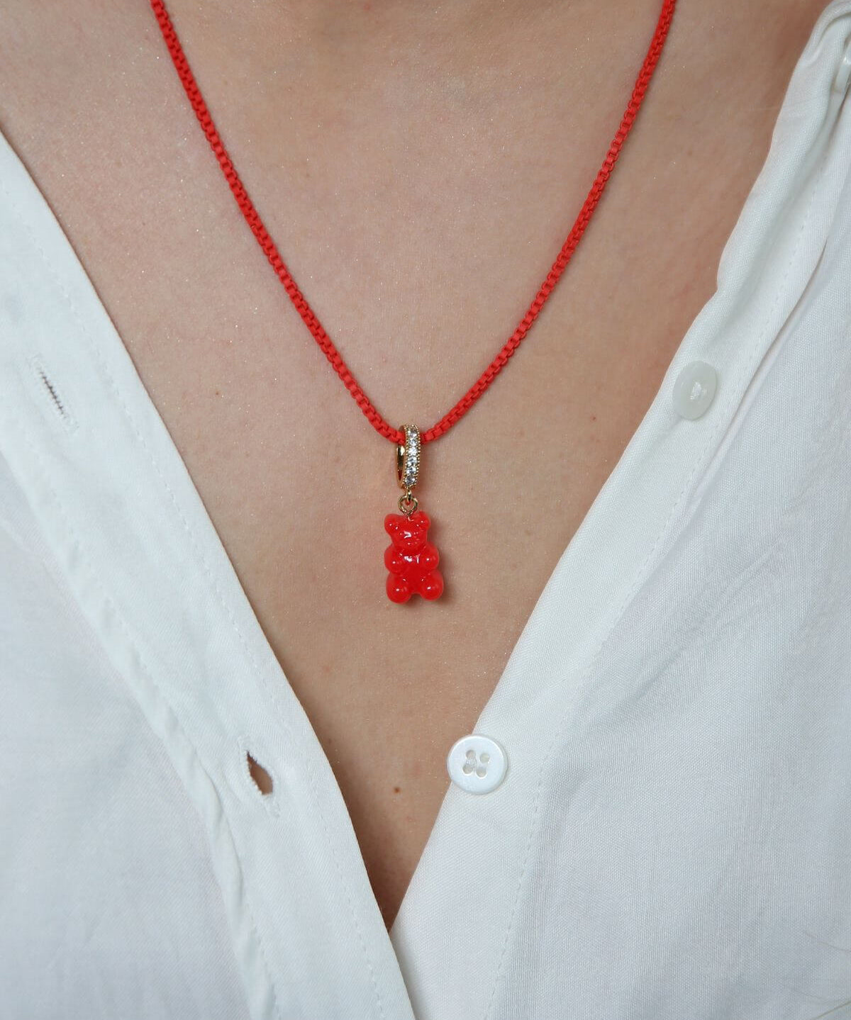 Crystal Haze red Nostalgia Bear pendant worn on a thin red cord necklace, resting at the collarbone.