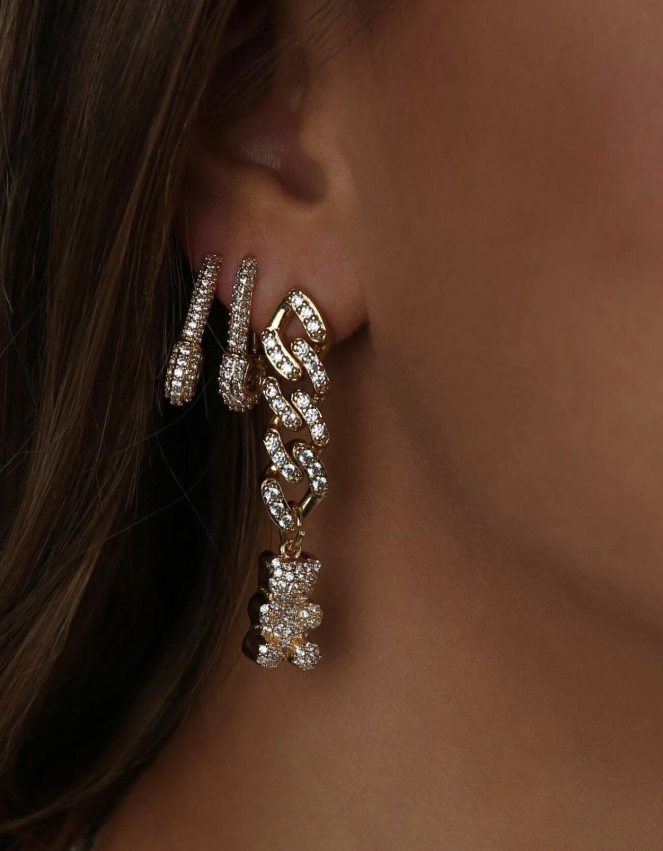 Close-up of the Crystal Haze Pavé Nostalgia gold earring worn on the ear, showing the pavé chain and bear charm.