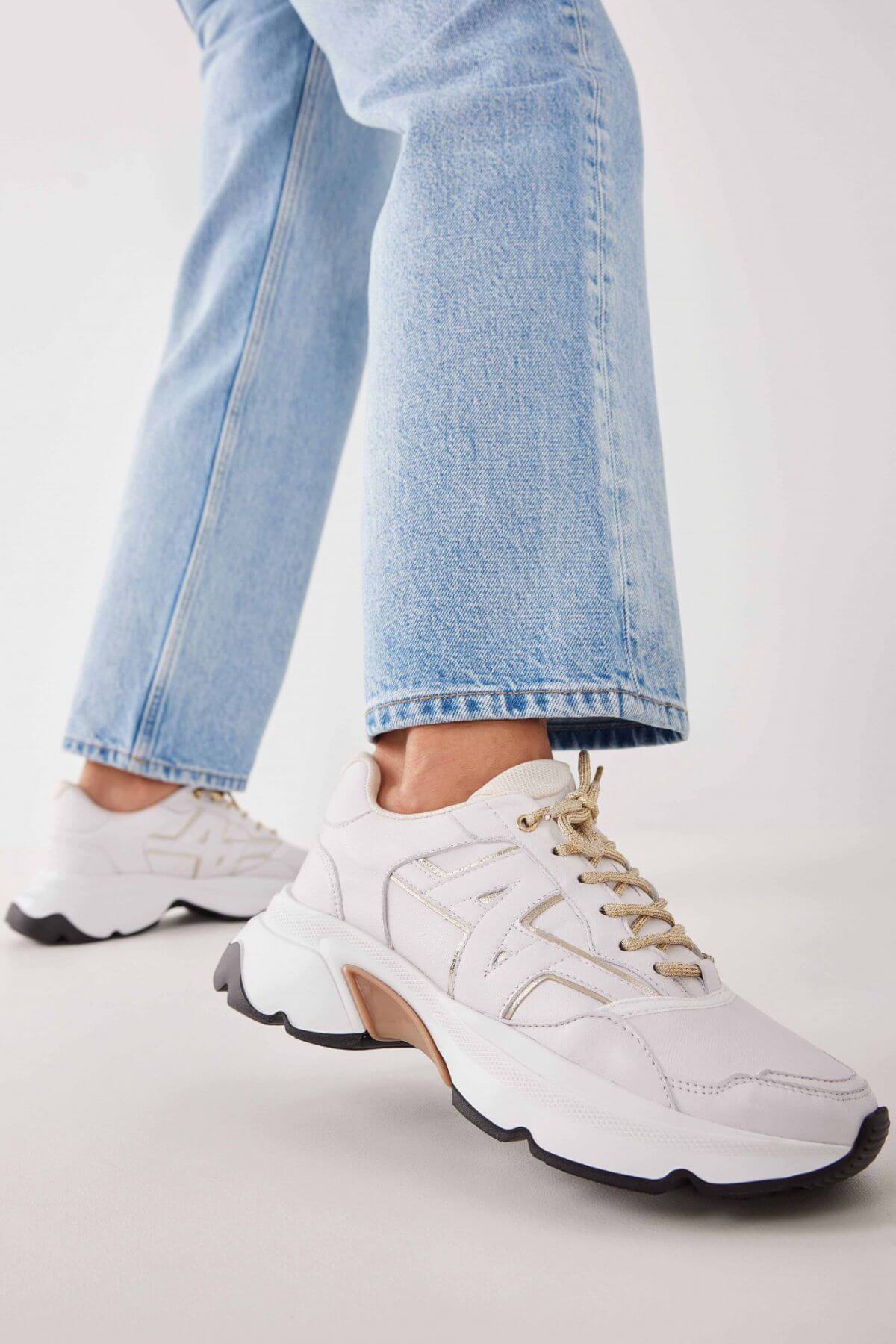 Woman wearing the Nubikk Ross Trek white sneakers with cropped blue jeans, street-style shot.