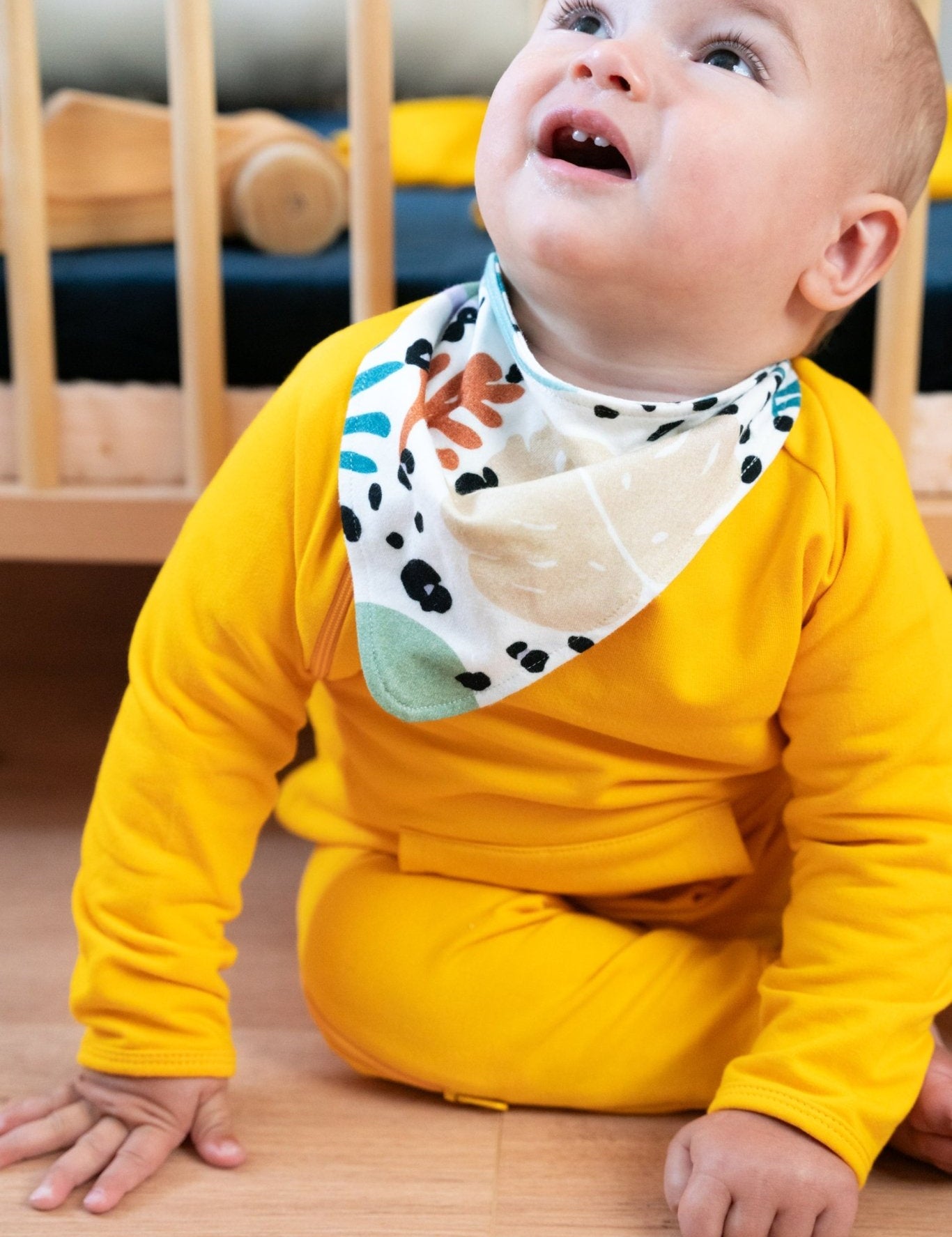 A baby wearing a bandana with tropical print by Swiss Brand Tilouco.