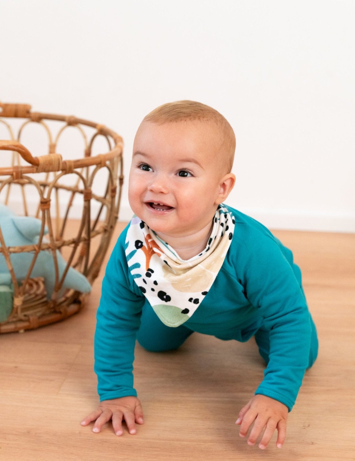 Ababy crawling on the floor with a bandana around his neck