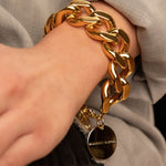 Woman wearing Vanessa Baroni's elegant gold flat chain bracelet, showcasing a modern design with chunky links and a secure gold clasp.